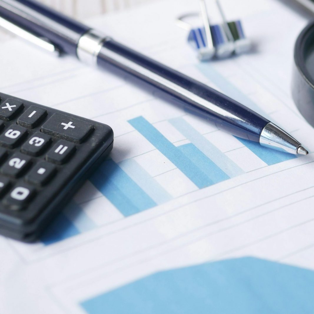 Close-up of calculator, pen, and magnifying glass on financial documents.